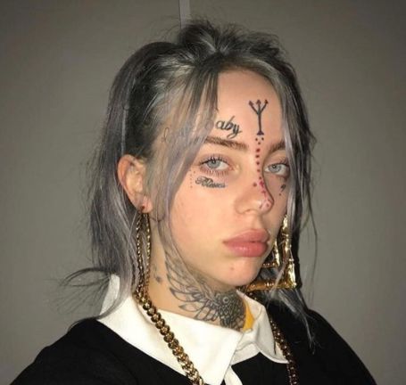 billie in a black short gold chains with face tattoos edited onto her by fans 